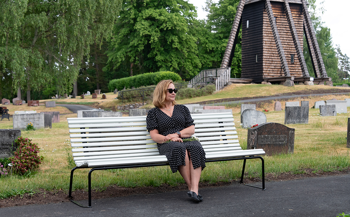 Woman relaxing on the Stockholm park bench on a cemetary.
